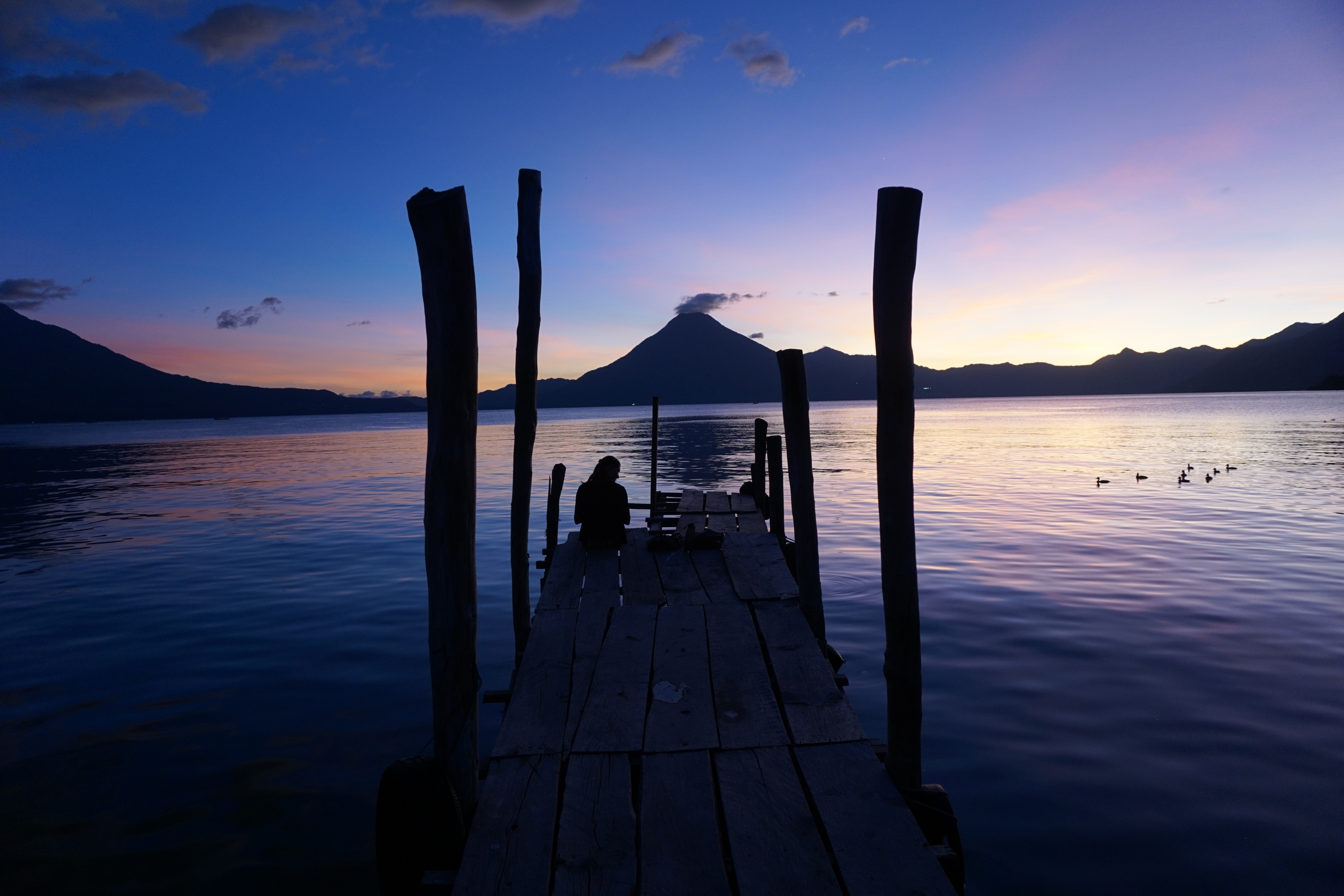 person sitting at a dock looking at a peaceful landscape