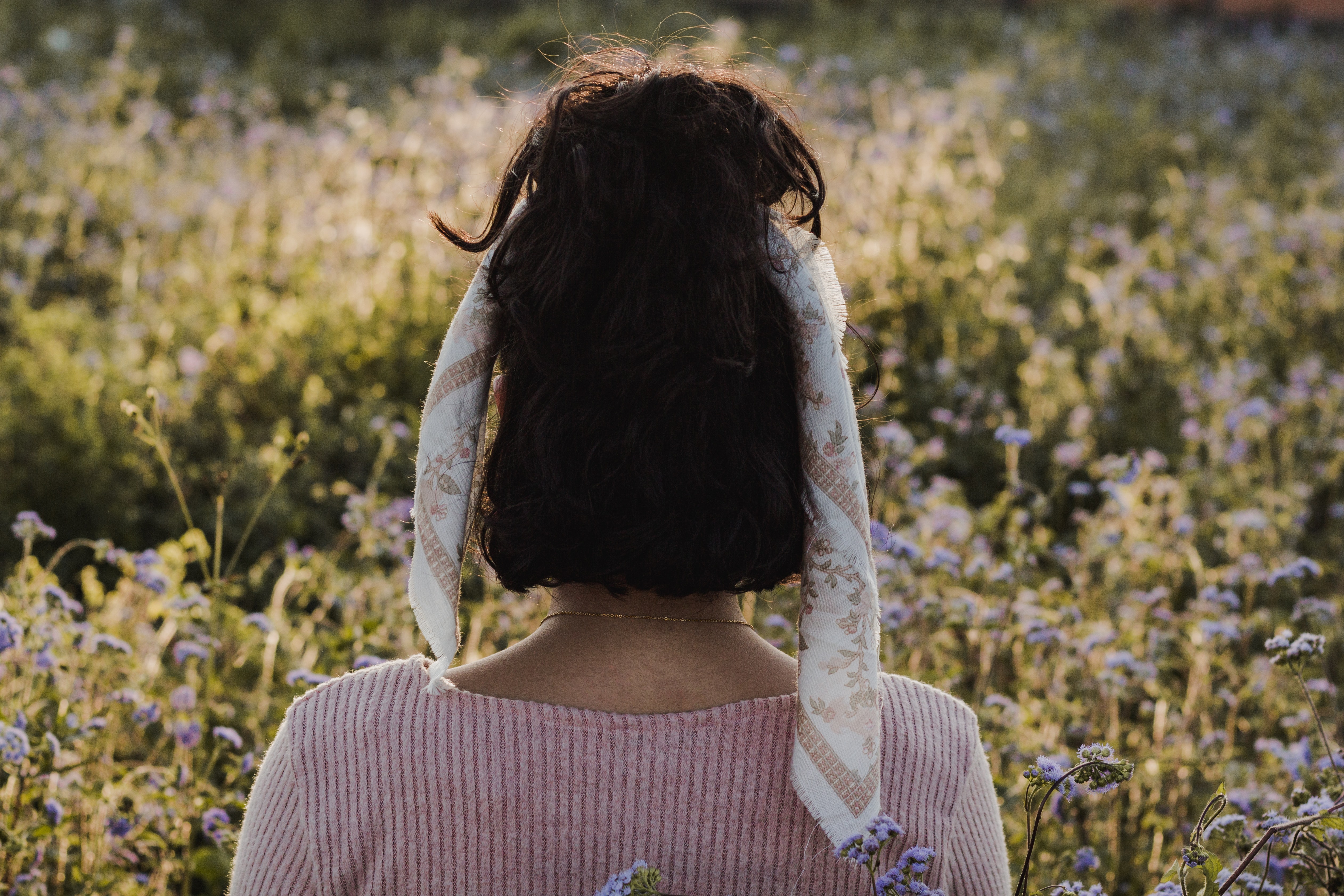 View of young girl from behind in field of flowers 