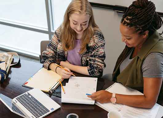 covenant house staff and student sitting at table with laptop and books